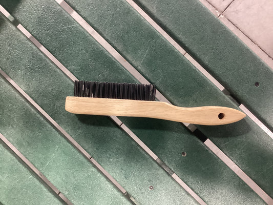 A wooden brush resting on a green bench.