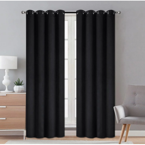Black blackout curtains hanging in a room, blocking out sunlight and providing privacy.