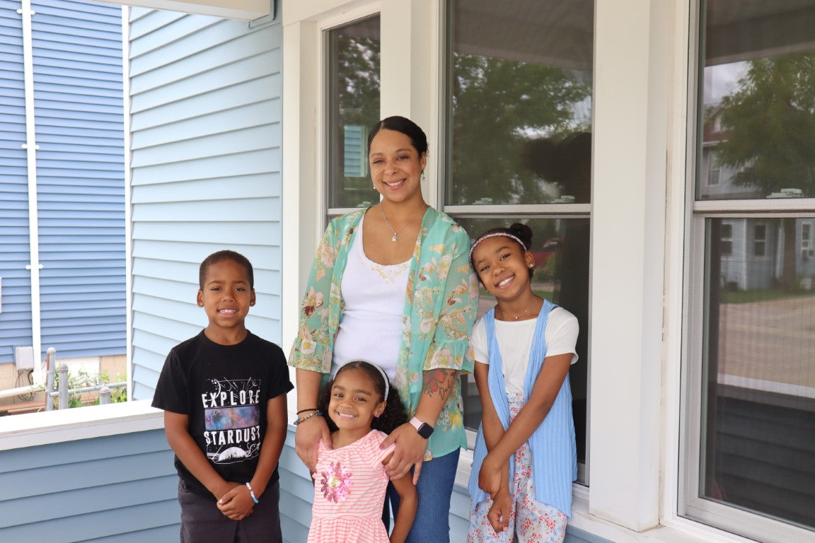 A woman and three children standing on a porch, enjoying a moment together.