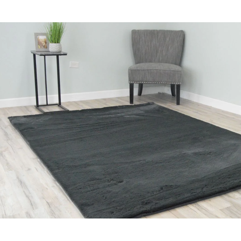 A 5x8 Charcoal colored rug in a room with a chair, desk, picture, and plant